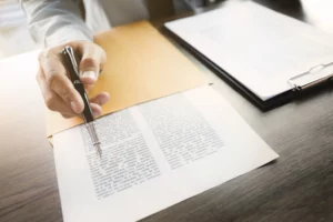 Hand reviewing a printed legal document, illustrating what happens to pending lawsuits when filing Chapter 13 bankruptcy in Oregon.