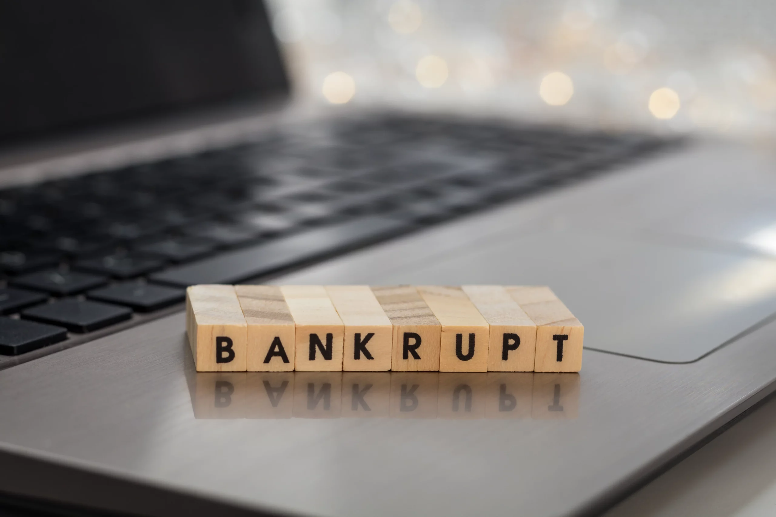 Wooden “BANKRUPT” letters on a laptop, illustrating the Oregon bankruptcy means test and eligibility requirements.